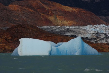 Golden stones and white blue icebergs on a grey lake